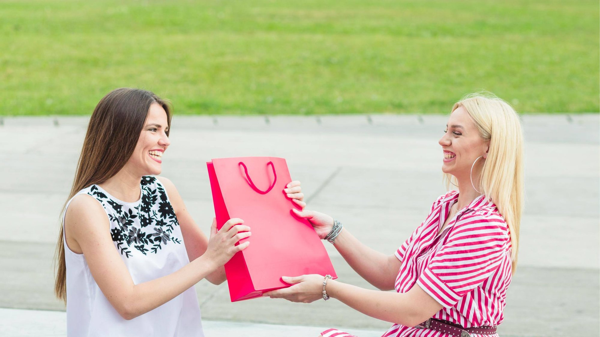 smiling-female-friend-giving-pink-paper-bag-his-friend (1)